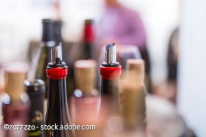 open wine bottles, flexible wine pourer, glasses, corks with blurred background at the wine tasting event